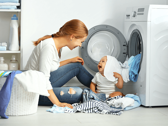 Matka s dieťatkom perie oblečenie v práčke